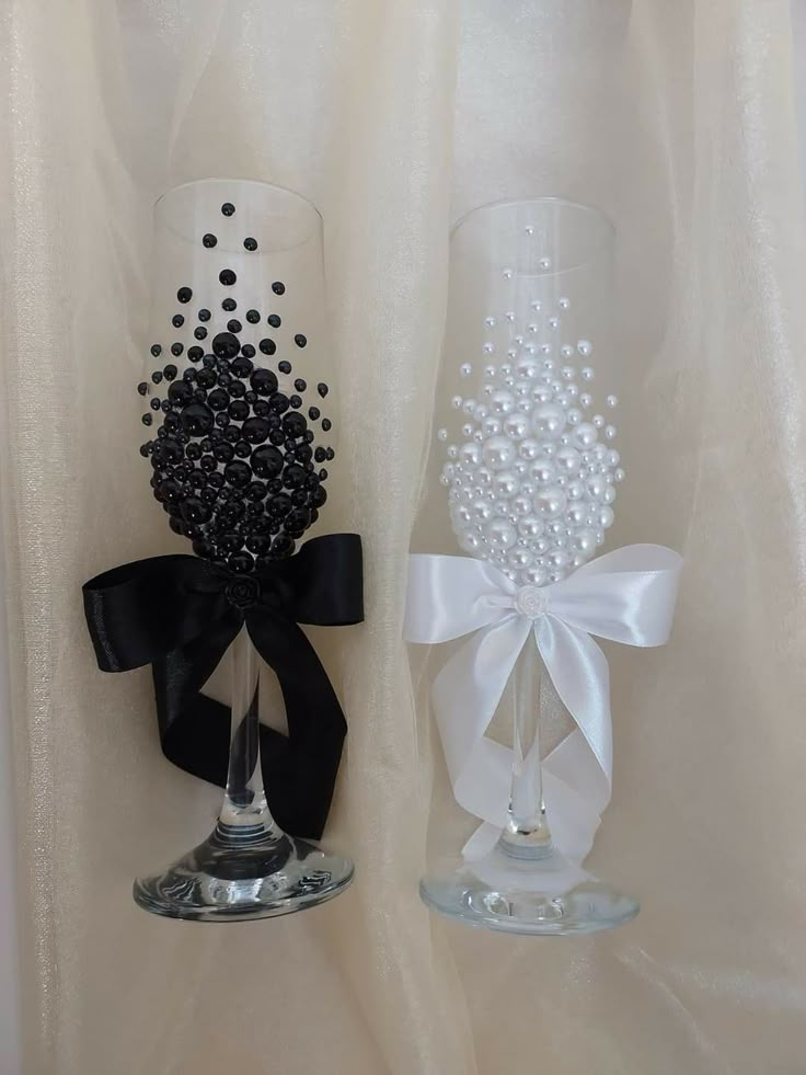 two wine glasses decorated with black and white pearls