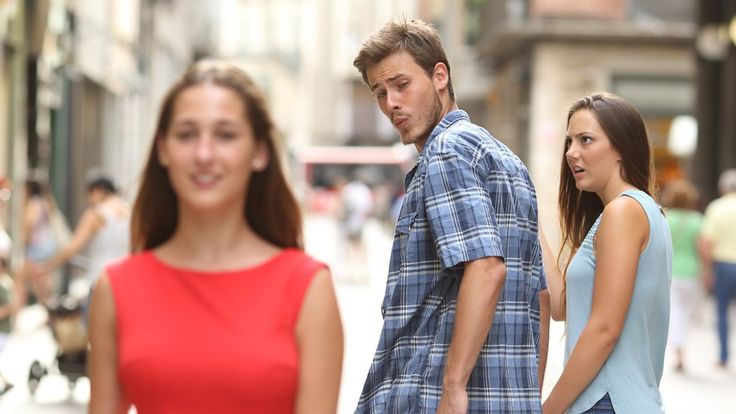 two women and a man walking down the street in front of them, one is looking at the camera