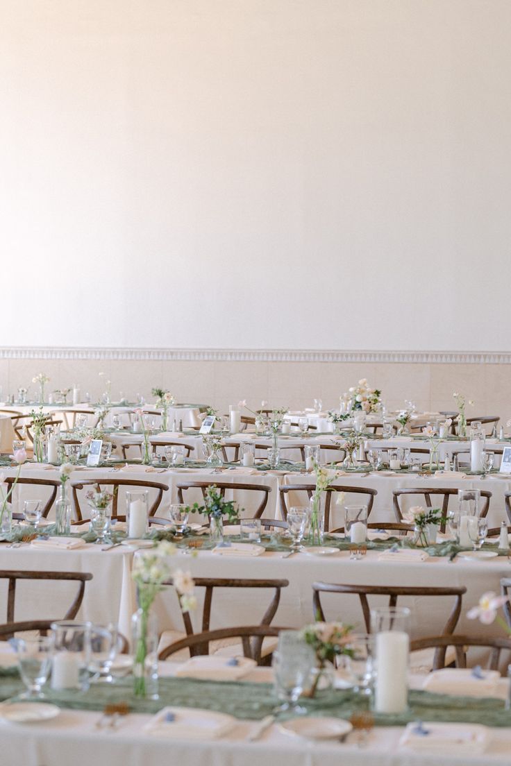 the tables are set up with white linens and green centerpieces on them