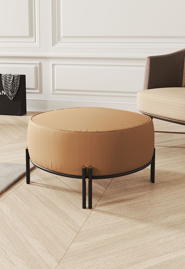 a round ottoman sitting on top of a hard wood floor next to a white wall