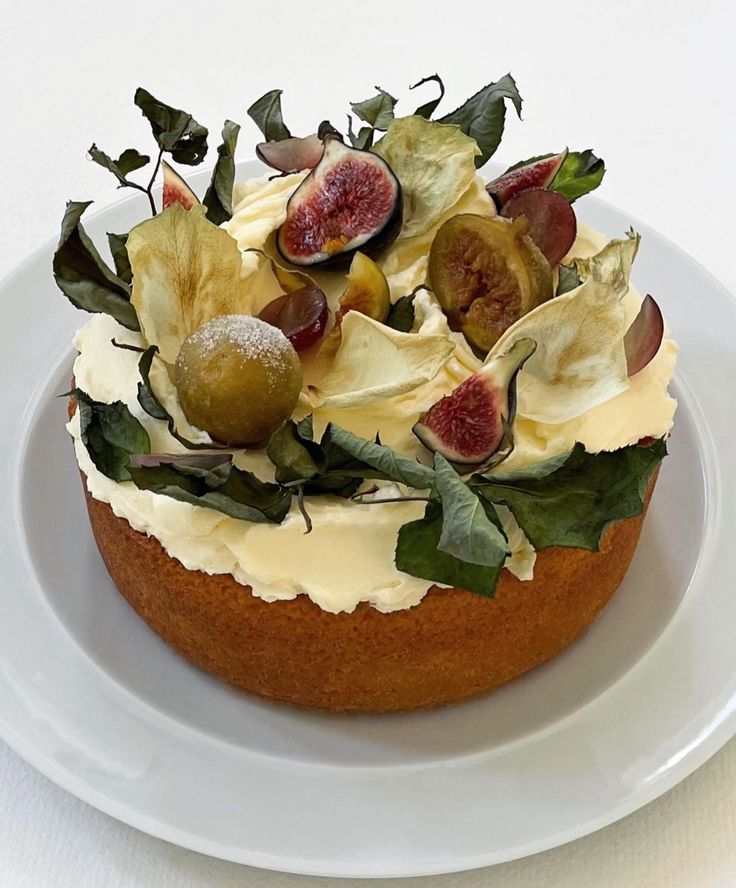 a white plate topped with a cake covered in frosting and figs on top of it