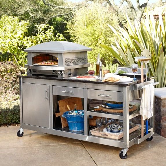 an outdoor bbq grill with food and drinks on the outside patio, next to a potted plant