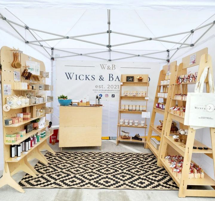 the inside of a store with wooden shelves and various items on display under a white tent