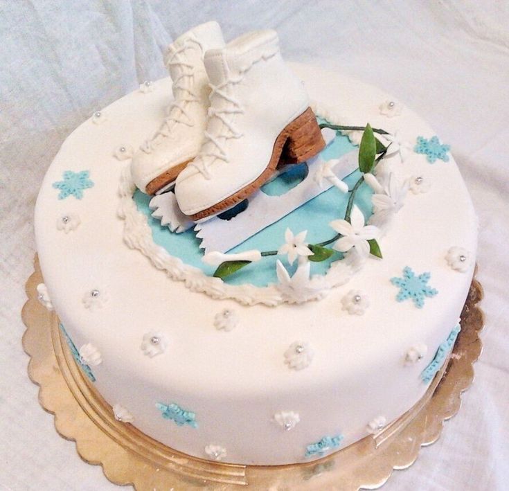 a cake decorated with ice skates and flowers on a tablecloth covered table cloth