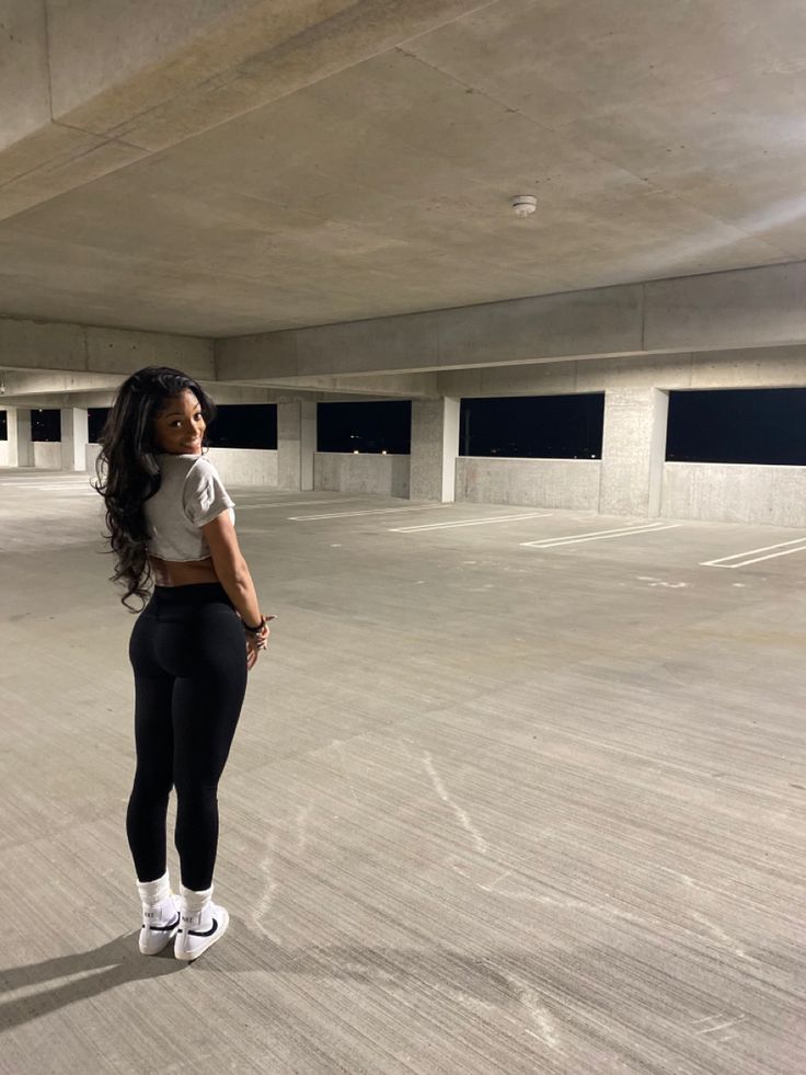 a woman standing in an empty parking garage