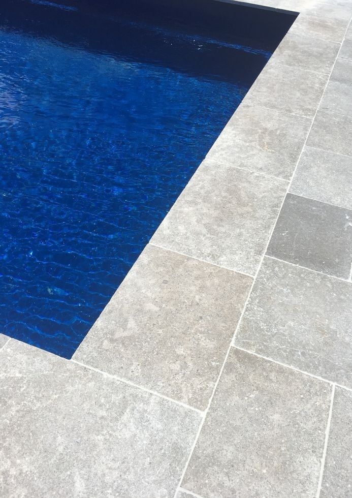 an empty swimming pool with blue water in the middle and tile flooring around it