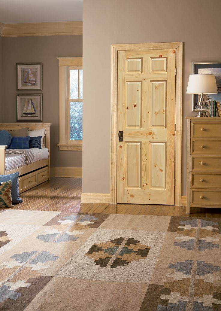 a bedroom with a bed, dresser and rug in front of the door that leads to another room