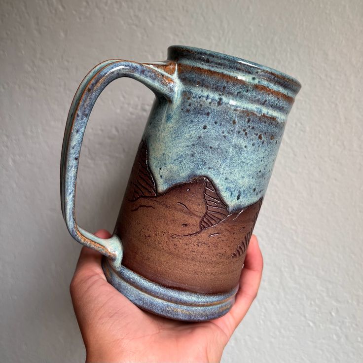 a hand holding a blue and brown coffee mug