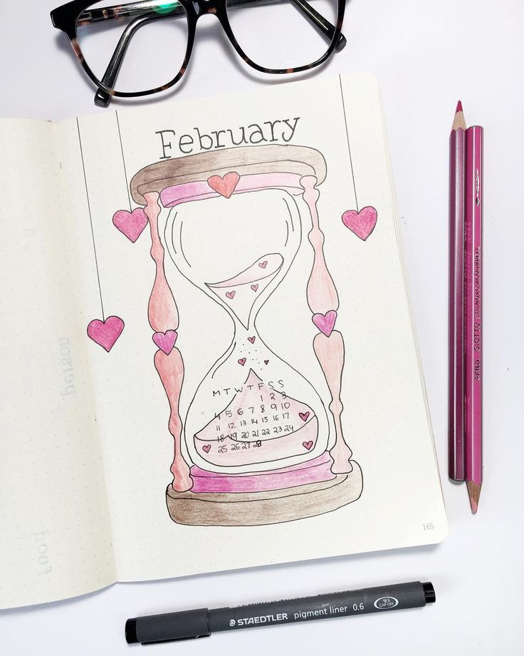 an open notebook with a drawing of a hourglass and pencils next to it