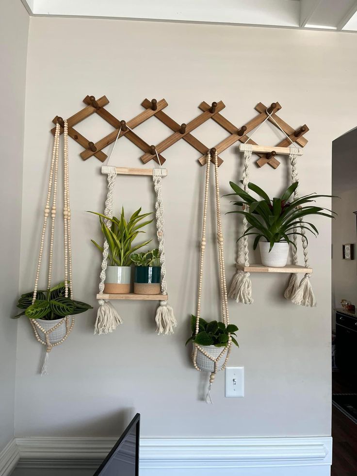 three hanging planters with plants on them in the corner of a room, one is made out of wood