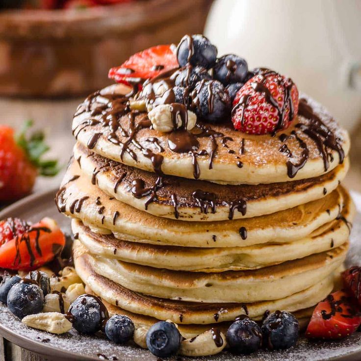 a stack of pancakes with chocolate sauce and strawberries