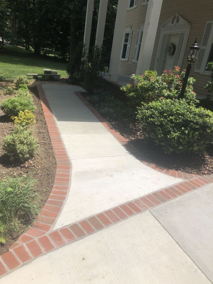 a walkway leading to a house with bushes and shrubs around it