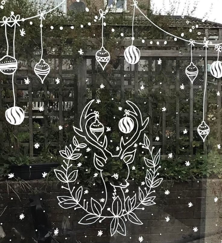 a window decorated with christmas decorations and ornaments hanging from the side of it, in front of a house