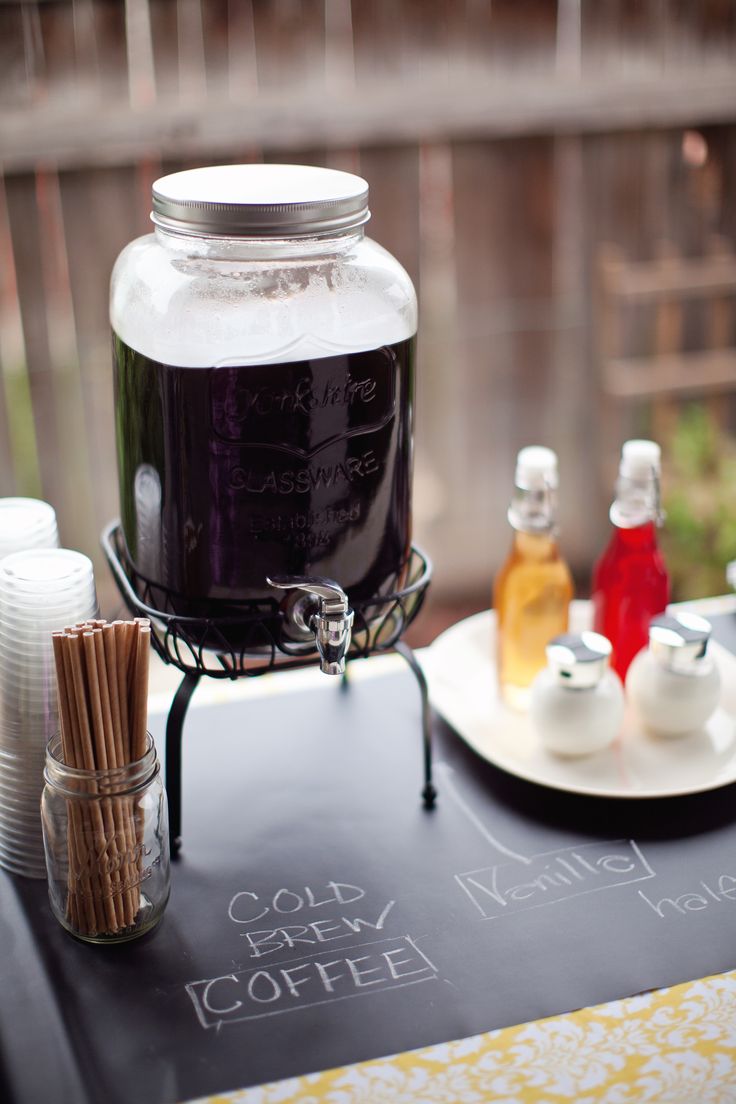 a table topped with a glass jar filled with liquid next to cups and saucers