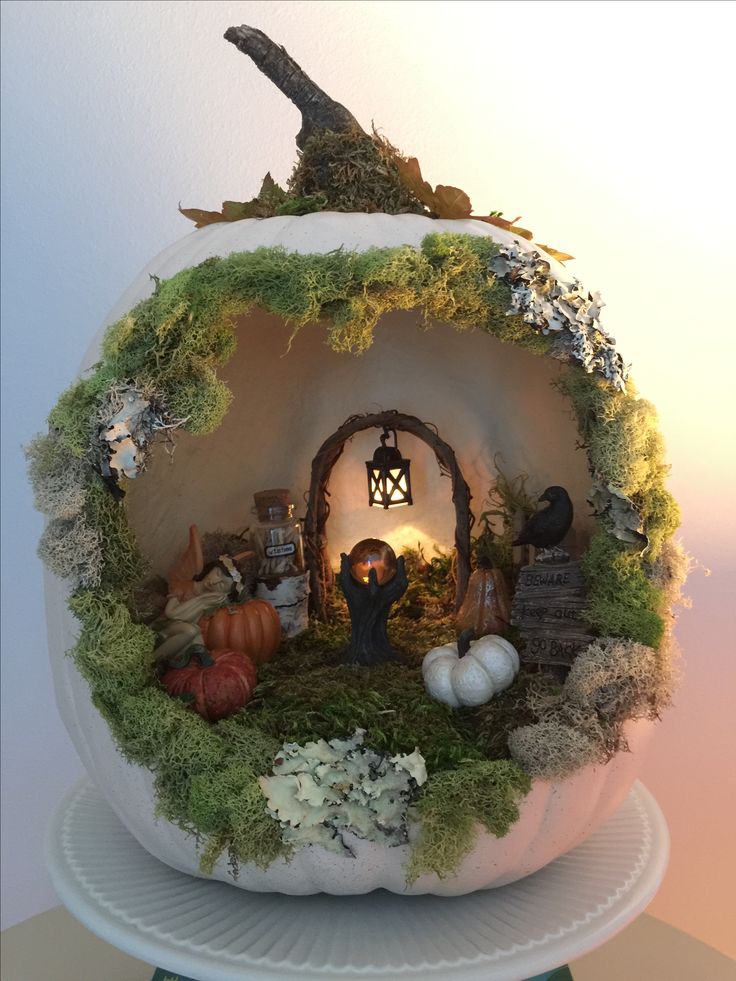 a fake pumpkin with an image of a man in the center surrounded by plants and mushrooms