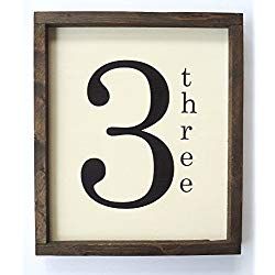 a wooden framed sign with the number three in black and white, hanging on a wall