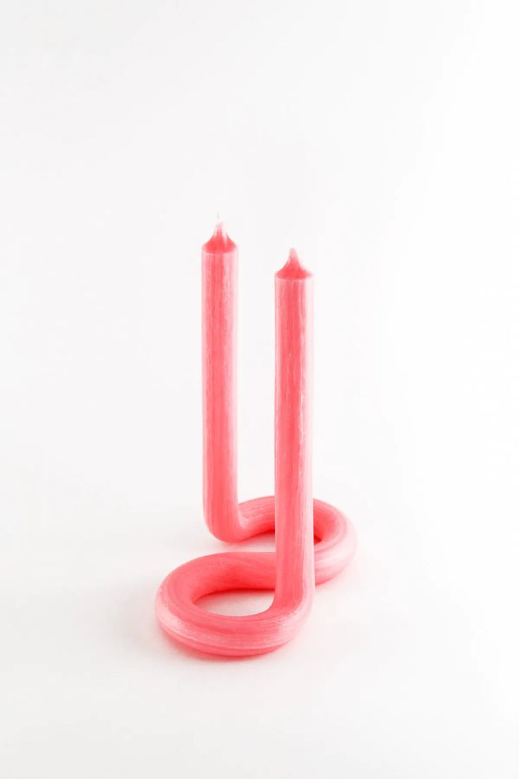 two pink candles sitting next to each other on top of a white surface with one candle in the middle