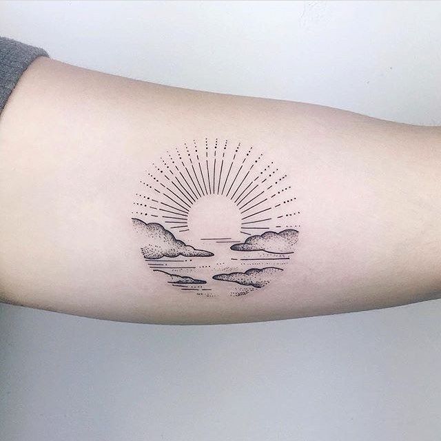 a woman's arm with a sun and clouds tattoo on the left inner arm