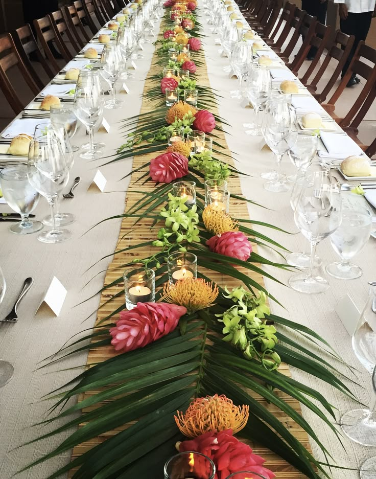 a long table is set up with flowers and place settings for dinner guests to enjoy