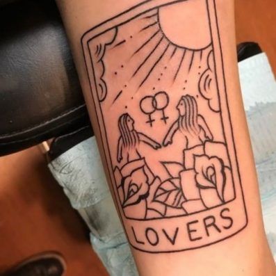 a person with a tattoo on their arm has a tarot card in front of them