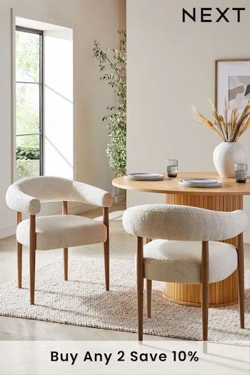 two chairs and a round table in a room with white carpeted flooring next to a window