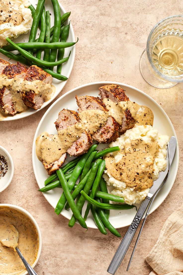 two plates with meat, green beans and mashed potatoes