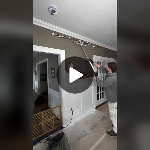 a man is painting the inside of a house with gray walls and white trimming