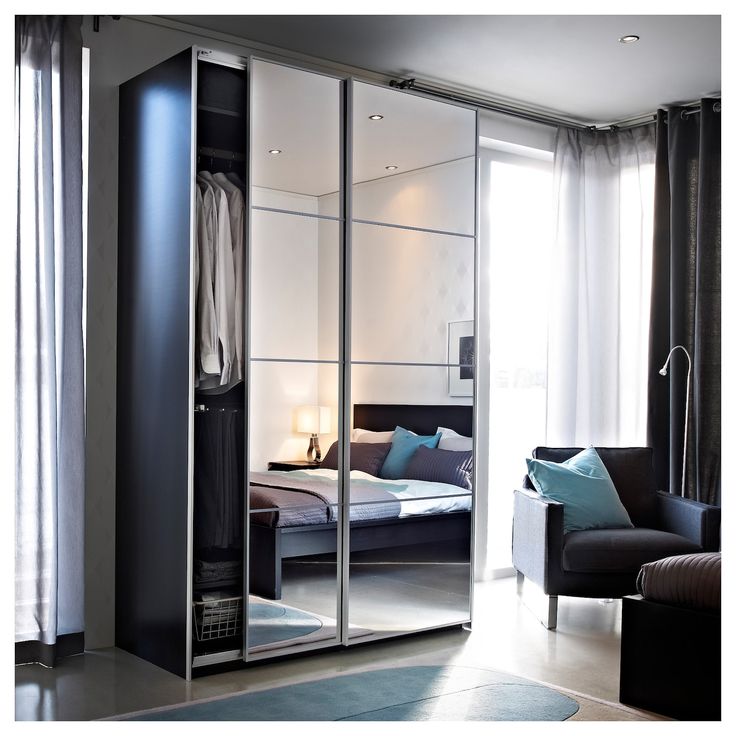 a bedroom with a bed, chair and mirrored closet doors in the middle of it