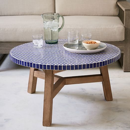 a blue and white coffee table sitting in front of a couch with two glasses on it