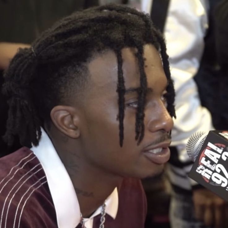 a young man with dreadlocks on his head is talking into a radio microphone