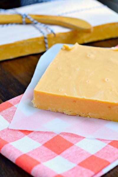 a piece of cheese sitting on top of a red and white checkered napkin