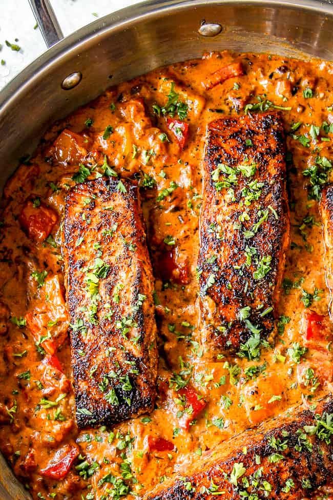 blackened salmon in creamy tomato sauce with parsley on the side and text overlay that reads, blackened salmon in creamy tomato sauce