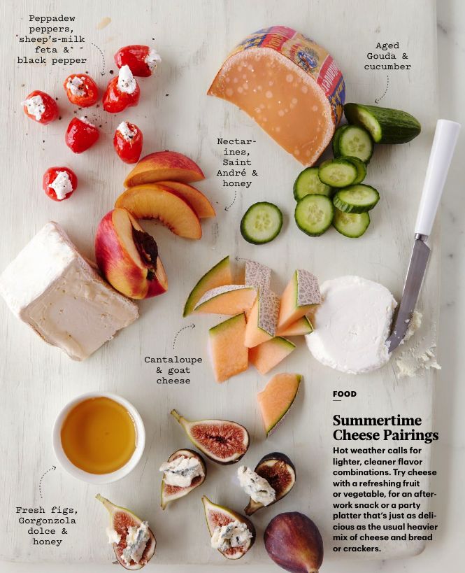 assorted fruits and vegetables on a cutting board with cheese, tomatoes, cucumbers, and crackers