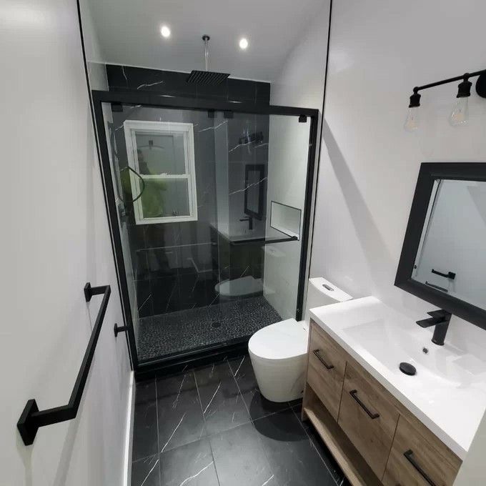 a bathroom with a toilet, sink and shower stall in the middle of the room