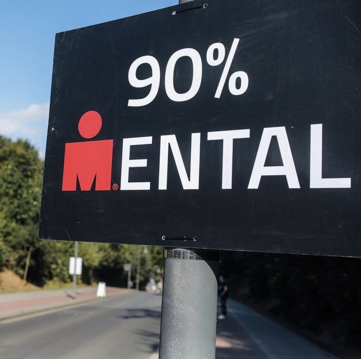 a sign that says 90 % mental on the side of a road with trees in the background