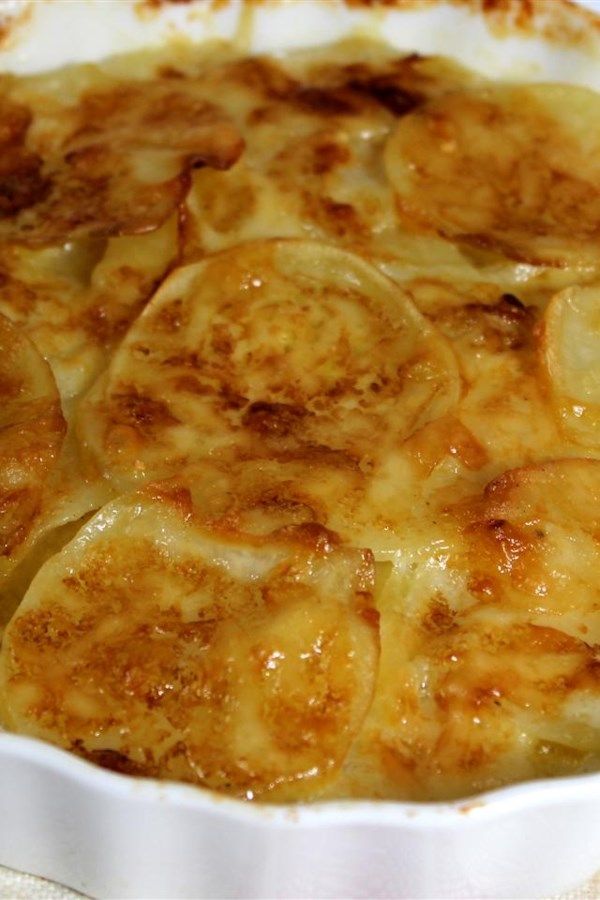 a casserole dish filled with potatoes on a white tablecloth covered table cloth