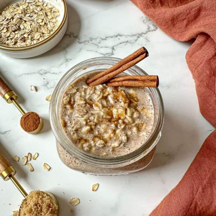 a glass jar filled with oatmeal and cinnamon sticks on top of a table