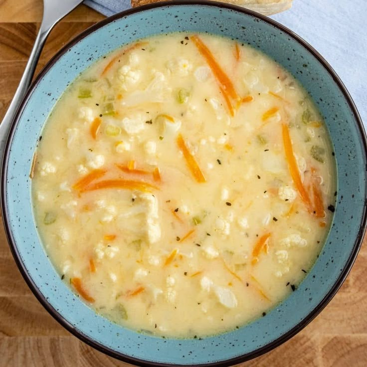 a blue bowl filled with soup next to a piece of bread