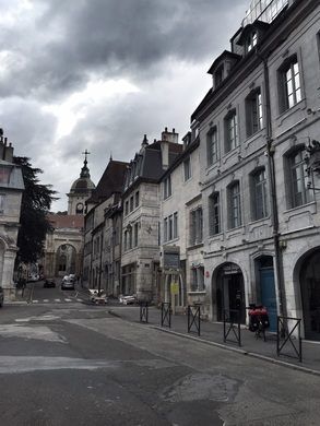 an empty street with buildings on both sides and dark clouds in the sky over them