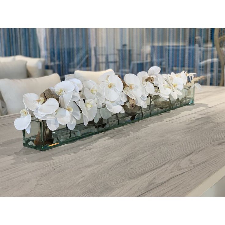 white flowers are arranged on a glass shelf