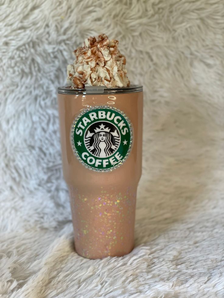 a starbucks cup with some kind of topping on it's lid sitting on a fluffy white blanket