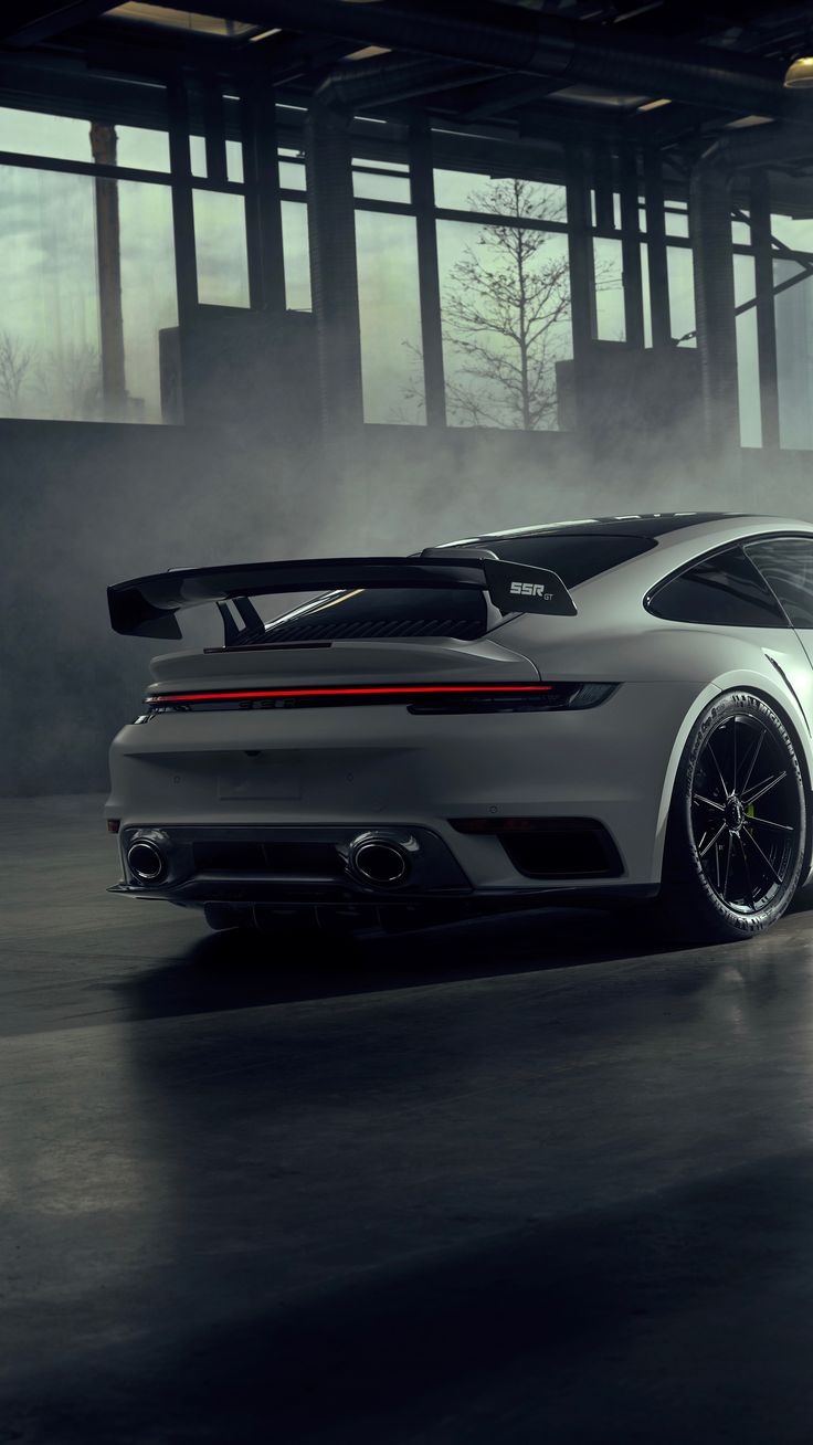 a white porsche sports car driving through a foggy parking garage with its doors open