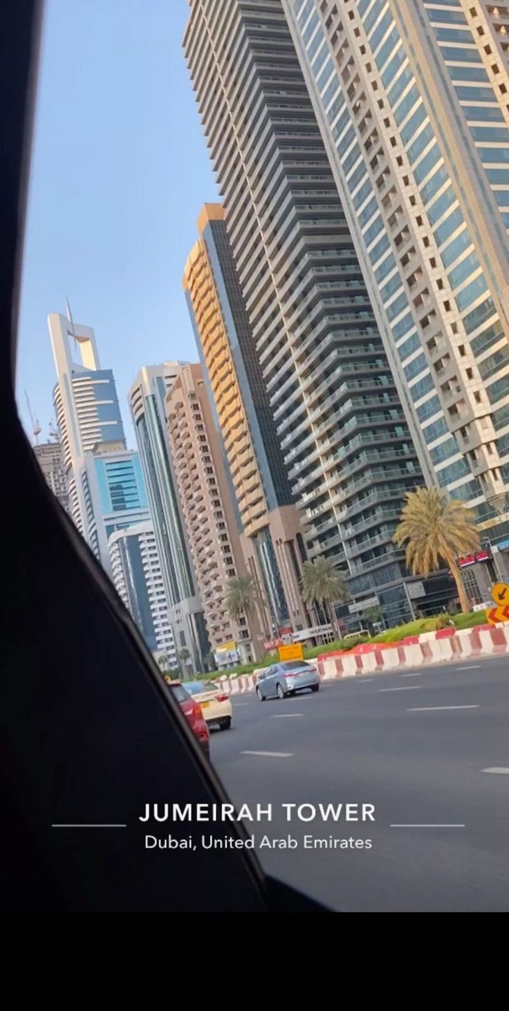 the view from inside a vehicle looking at some tall buildings