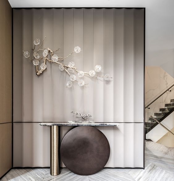 an elegant console table with flowers on it in the middle of a room that has striped walls