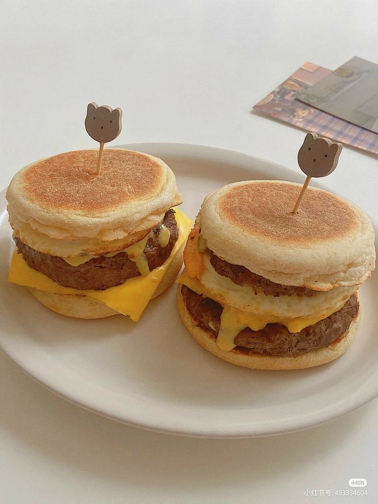 two cheeseburgers are sitting on a plate with toothpicks in the middle