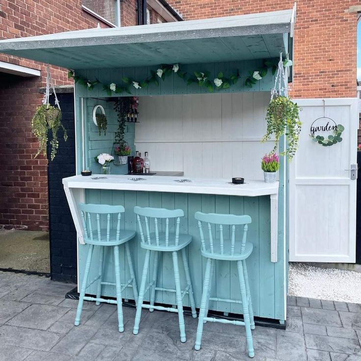 an outdoor bar with three stools in front of it