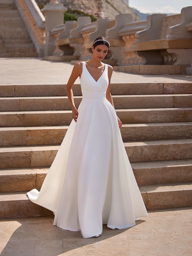 a woman in a white dress standing on some steps