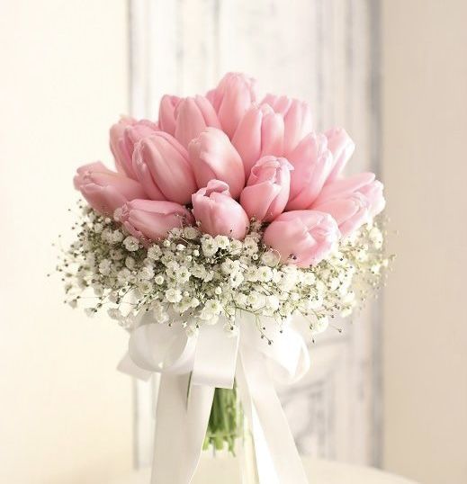 a vase filled with pink tulips and baby's breath