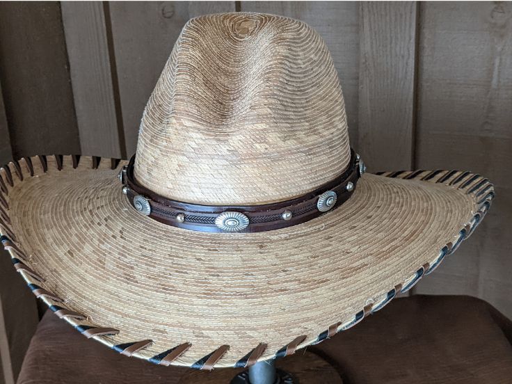 Brown leather has been trimmed with imprinted brown leather and accented with sunburst sliders and shiny nailspots. The hatband has brown leather lace and an antler bead that slides the hatband securely around the crown of your hat. It is 23" long and 20mm wide. Hat not included. Luxury Leather Hat Bands With Curved Brim, Custom Adjustable Brown Hat Bands, Adjustable Brown Country Style Hat Bands, Distressed Brown Adjustable Hat For Western-themed Events, Custom Brown Hat Bands For Ranch, Brown High Crown Country Hat, High Crown Brown Country Hat, Adjustable Distressed Brown Hats For Rodeo, Adjustable Distressed Brown Country Hat