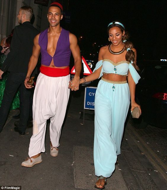 a man and woman are walking down the street holding hands while dressed in belly wraps